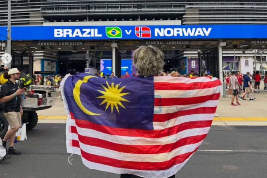 Lelaki tersbeut turut mengibarkan bendera Jalur Gemilang semasa menyaksikan perlawanan antara Brazil dan Norway.